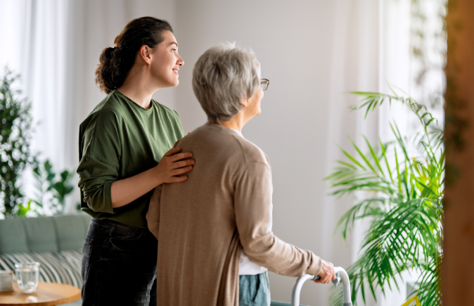 Older woman with walker and caregiver in brightly lit room